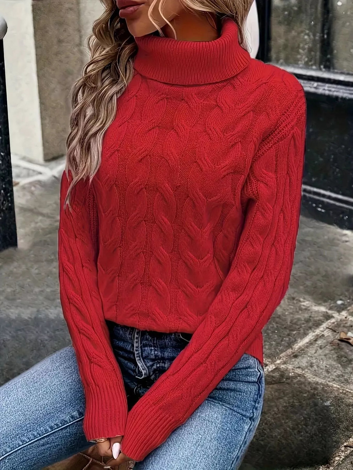 Woman wearing a red cable knit turtleneck sweater with jeans