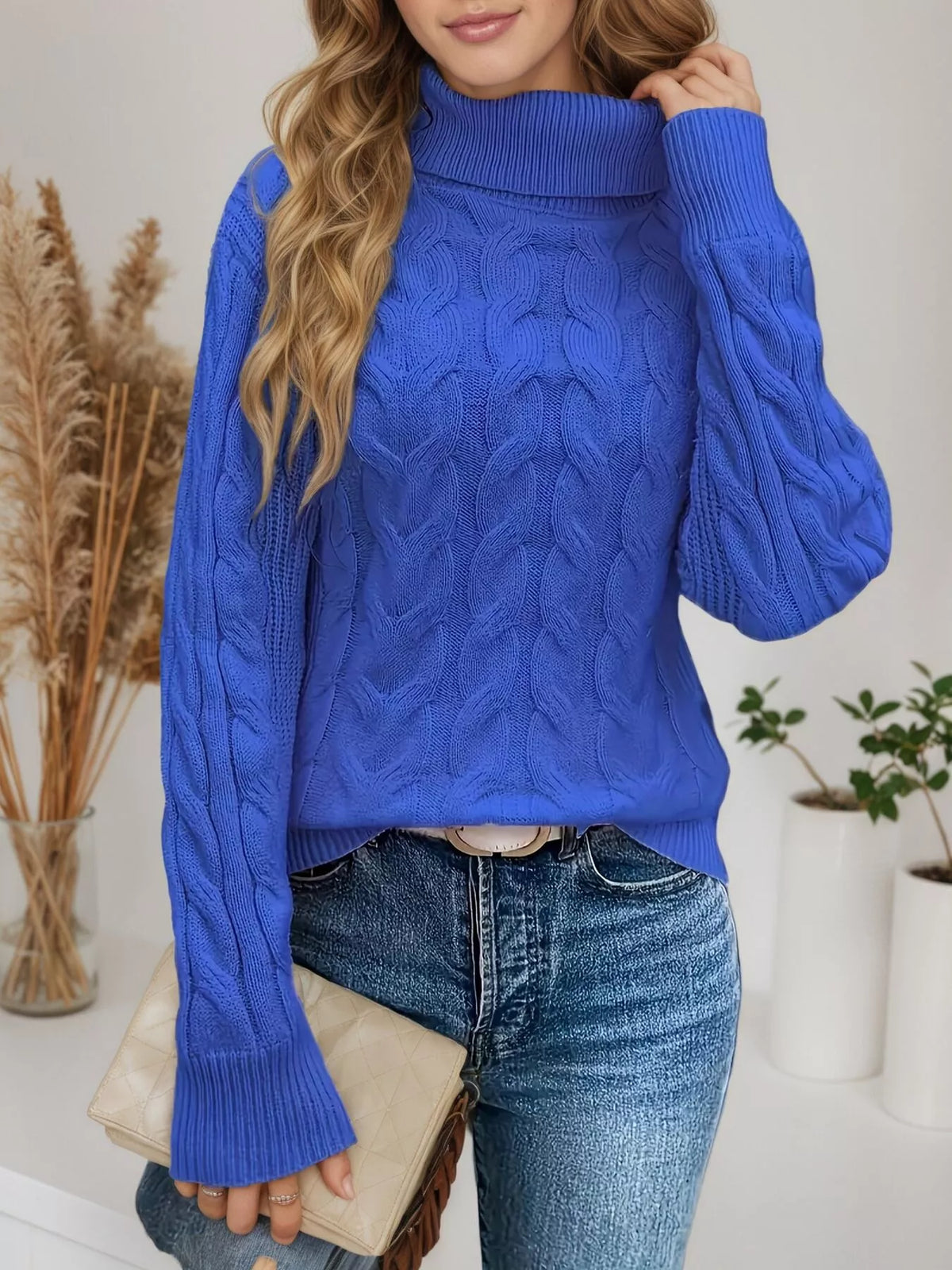 Woman wearing a royal blue cable knit turtleneck sweater with jeans
