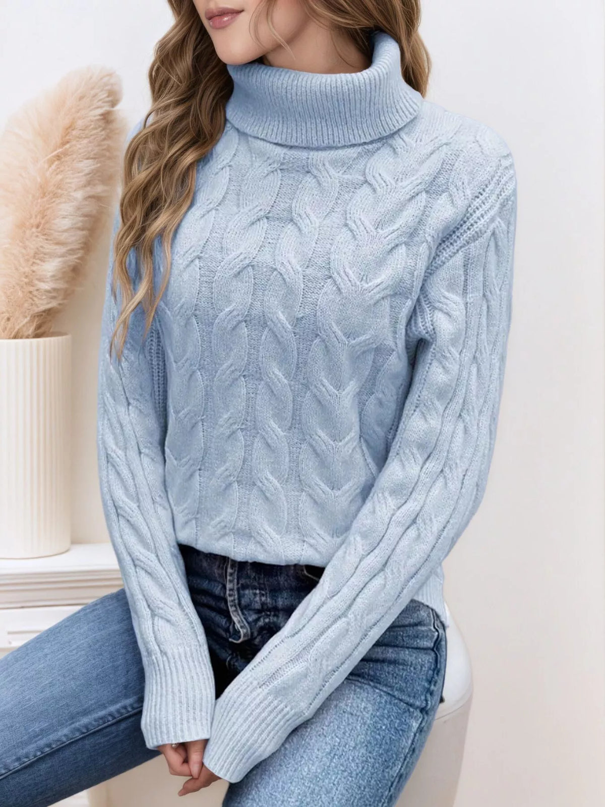 Woman wearing a sky blue cable knit turtleneck sweater with jeans