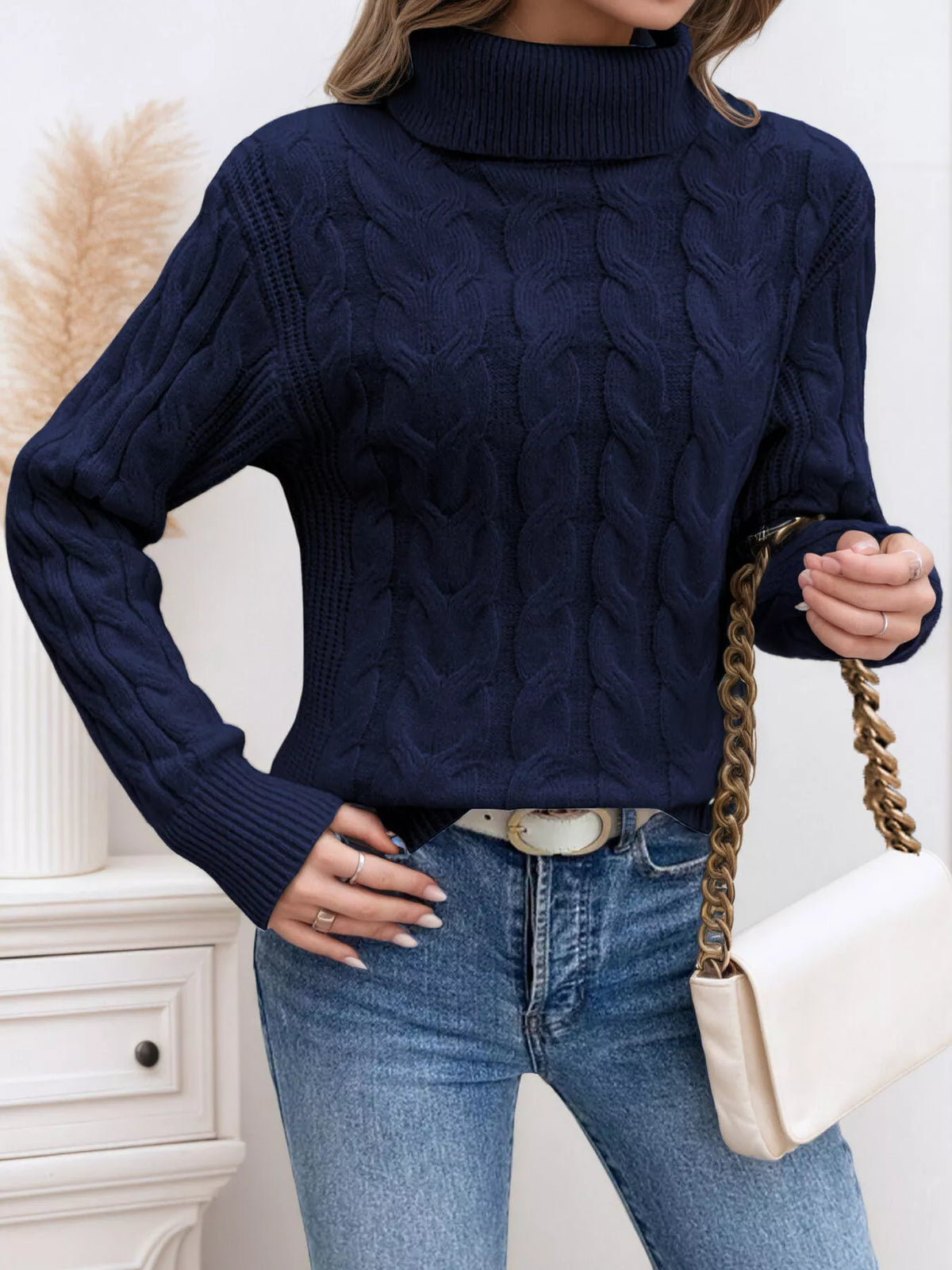 Woman wearing a dark blue cable knit turtleneck sweater with jeans