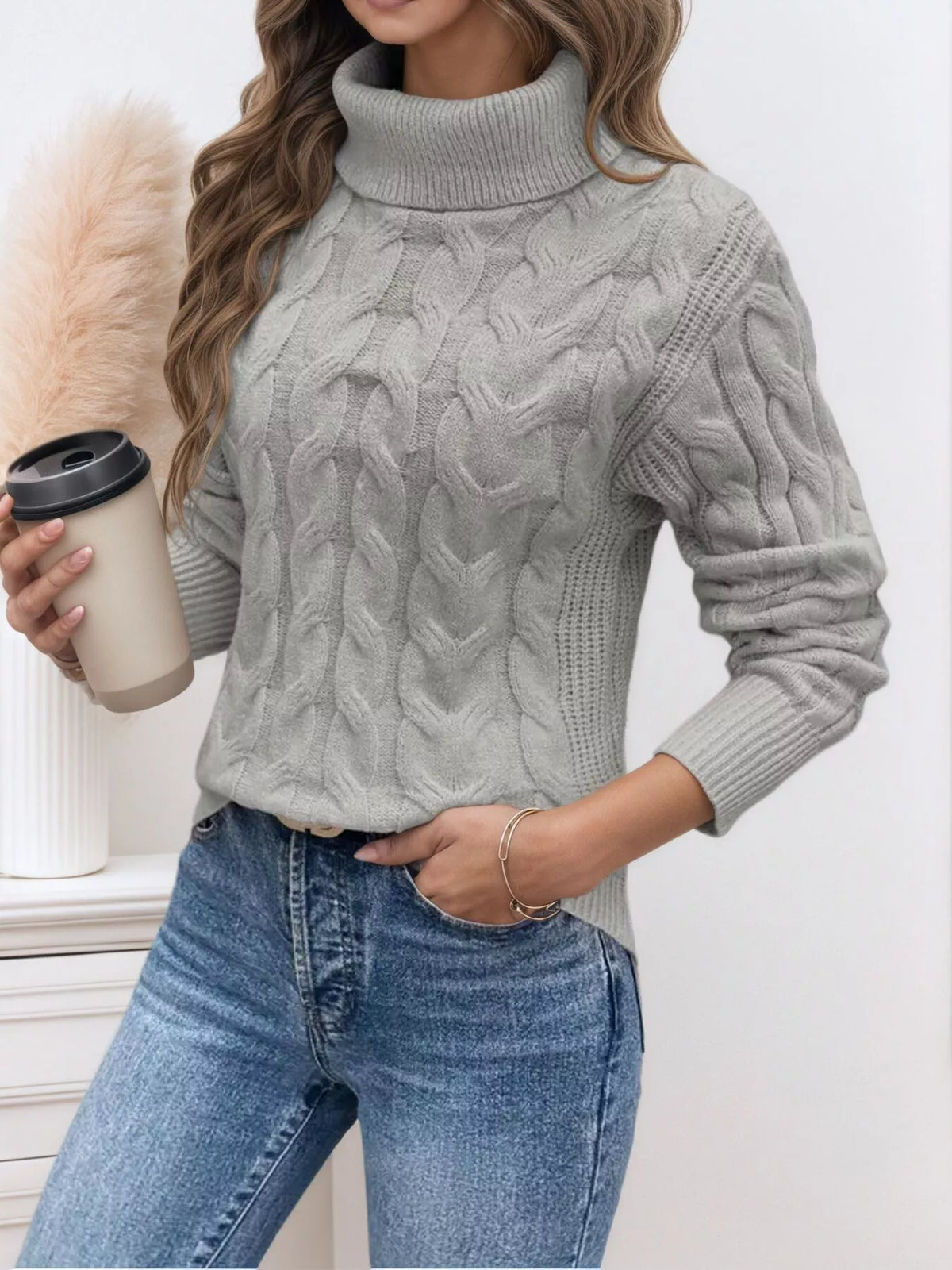 Woman wearing a grey cable knit turtleneck sweater with jeans
