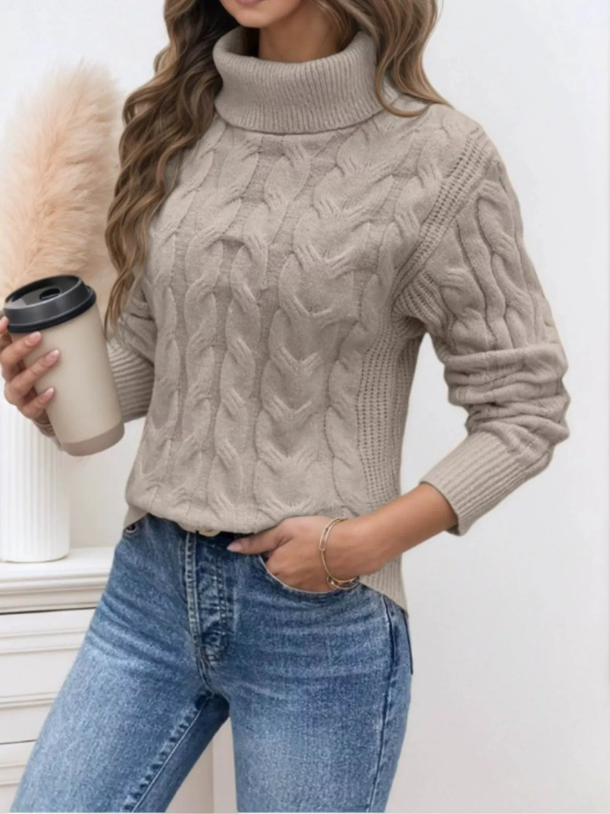 Woman wearing a khaki cable knit turtleneck sweater with jeans