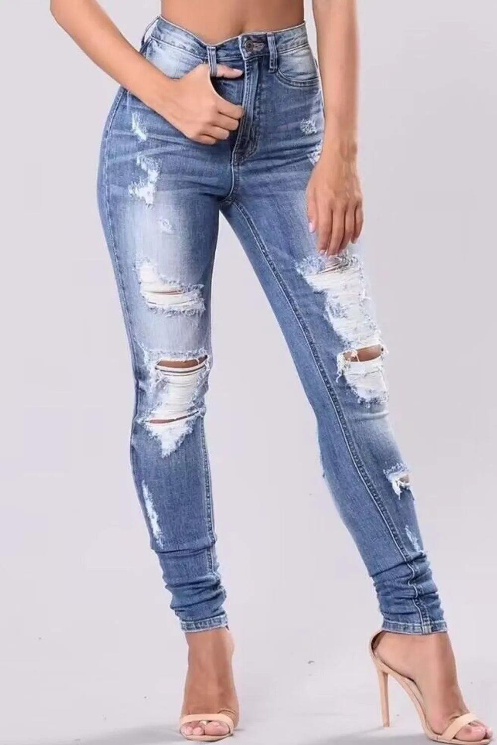 Woman wearing light blue distressed skinny jeans with ripped detailing